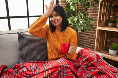 Kanepede oturan Latin kökenli genç kadın evde kahve içerken yanlışlıkla eli başının üstüne düşmüş, hatayı hatırla. Unuttum, kötü hafıza kavramı. 