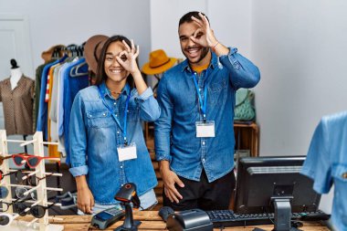Perakende mağazasında çalışan genç ırklar arası insanlar el hareketleriyle gülümsüyor, gözleriyle mutlu yüzle parmaklarının arasından bakıyor.. 