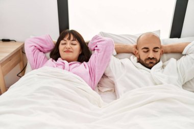 Genç İspanyol çift gülümsüyor, mutlu, elleri yatak odasının üstünde rahatlamış..