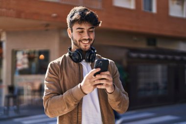 Sokakta akıllı telefon kullanan, kendine güvenen genç bir İspanyol.