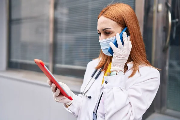 在医院里 年轻的高加索女医生戴着医疗面罩 在智能手机上使用触摸板交谈 — 图库照片