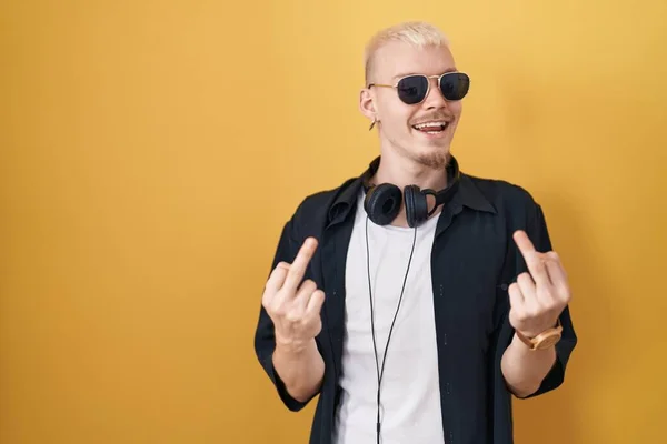 Young Caucasian Man Wearing Sunglasses Standing Yellow Background Showing Middle — Stok fotoğraf