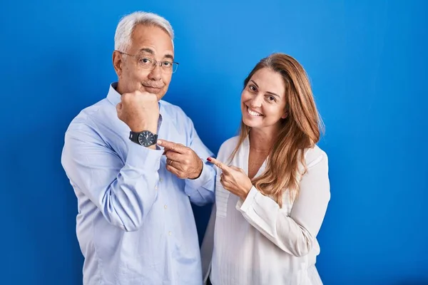 Middle Age Hispanic Couple Standing Blue Background Hurry Pointing Watch — kuvapankkivalokuva