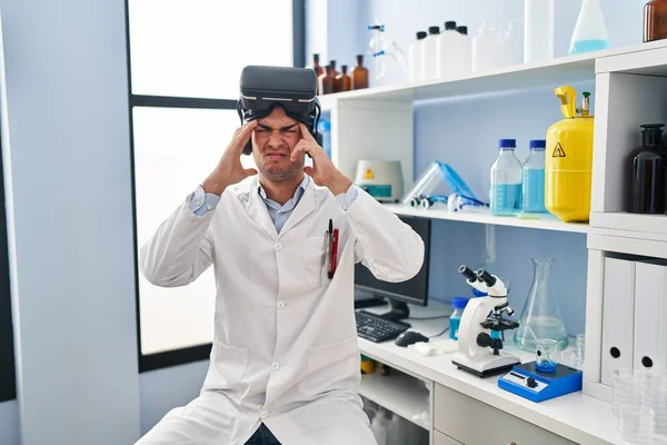 ストレスのために頭の上に手でVrの眼鏡をかけて科学研究所で働いている若いヒスパニック系の男 片頭痛 — ストック写真