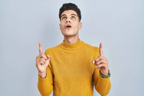 Young Hispanic Man Standing Blue Background Amazed Surprised Looking Pointing — Stockfoto
