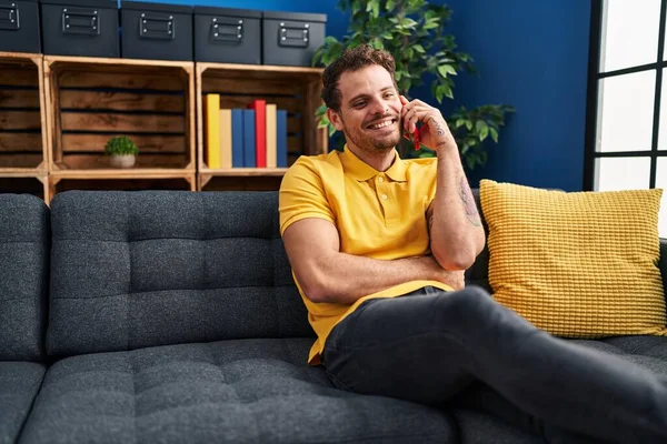 Young Hispanic Man Talking Smartphone Sitting Sofa Home — Fotografia de Stock