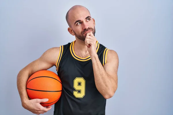 年轻的秃头男子 留着胡子 身穿篮球服 手托着下巴思考着问题 沉思着表情 脸上挂着沉思的笑容 怀疑概念 — 图库照片