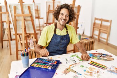 Resim stüdyosunda gülümseyen genç İspanyol sanatçı..