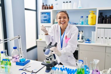 Laboratuvarda çalışan Latin asıllı genç bir kadın gururla bağırıyor zaferi ve başarıyı kutluyor. 