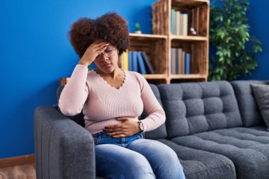 Afro-Amerikan kadın hastalığı, evdeki kanepede oturuyor.