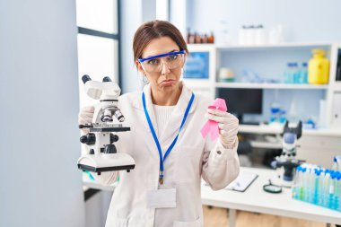 Genç esmer kadın, elinde pembe kurdele tutan bilim adamı laboratuvarında çalışıyor. Depresyonda ve endişe içinde, kızgın ve korkmuş bir halde. hüzünlü ifade. 