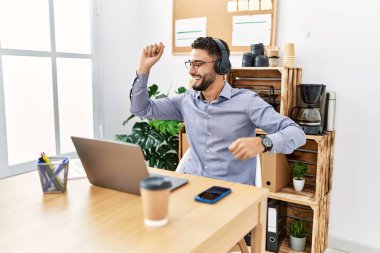 Genç Arap adam ofiste müzik dinlerken kendinden emin gülümsüyor.