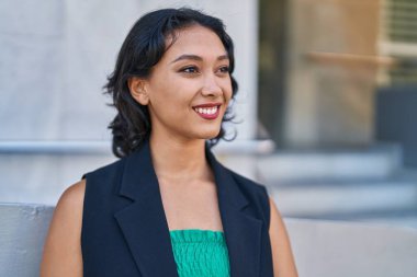 Young beautiful hispanic woman smiling confident looking to the side at street