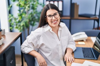 Ofiste çalışan genç İspanyol iş kadını laptopu kullanıyor.