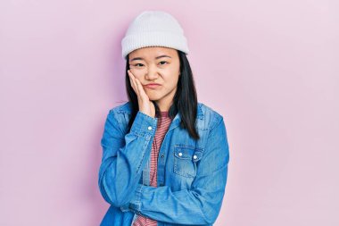 Young chinese girl wearing cute wool cap thinking looking tired and bored with depression problems with crossed arms. 