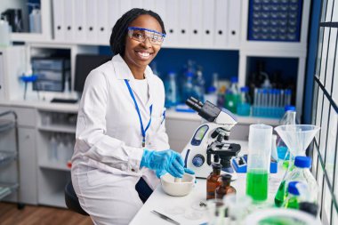 Bilim adamı üniforması giyen Afrikalı Amerikalı kadın laboratuarda çalışıyor.