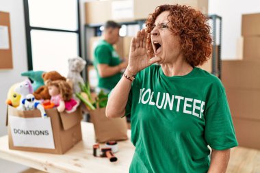 Bağışta gönüllü tişört giyen orta yaşlı bir kadın el ele tutuşup bağırıyor ve bağırıyor. iletişim konsepti. 
