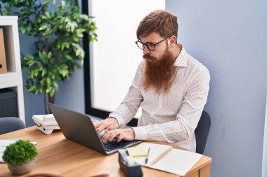 Young redhead man business worker using laptop working at office