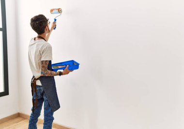 Evdeki silindiri kullanarak duvarı boyayan ressam.