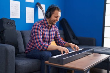 Young man musician playing piano keyboard at music studio