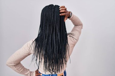 African woman with braids standing over white background backwards thinking about doubt with hand on head 