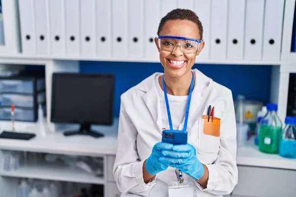 アフリカ系アメリカ人女性科学者が自信を持って笑顔で研究室でスマートフォンを — ストック写真