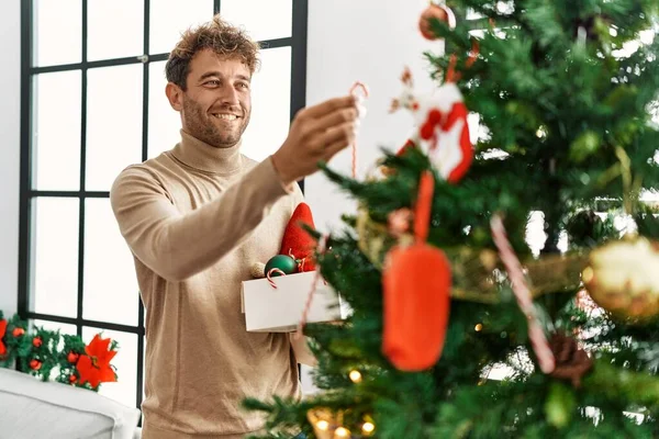 Νεαρός Ισπανός Άνδρας Χαμογελά Αυτοπεποίθηση Διακοσμώντας Χριστουγεννιάτικο Δέντρο Στο Σπίτι — Φωτογραφία Αρχείου
