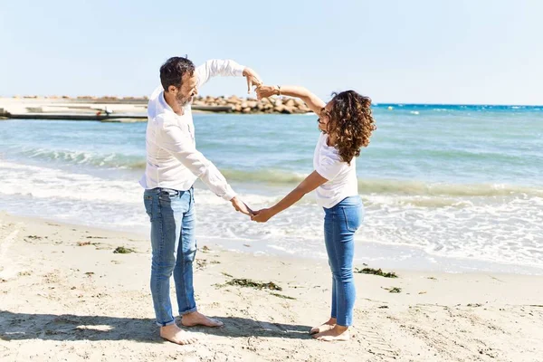 中年时 他那对惊慌失措的夫妇高兴地微笑着 在海滩上张开双臂做着心形 — 图库照片