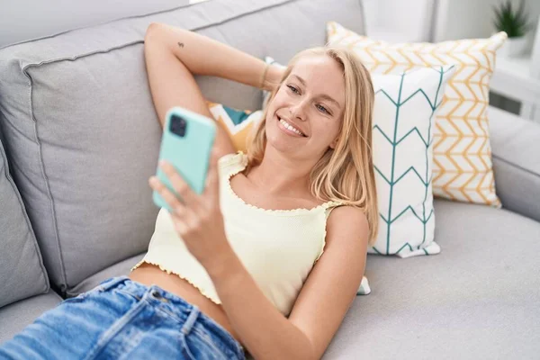 Mladá Blondýna Žena Pomocí Smartphone Ležící Pohovce Doma — Stock fotografie