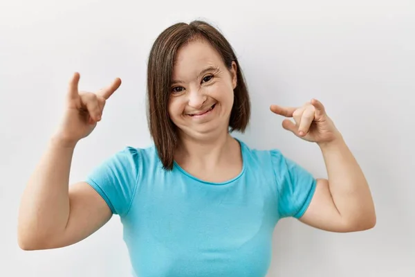 若いダウン症候群の女性は手を上げて岩のシンボルをやって狂気の表情で叫んで孤立した背景に立っている 音楽スター 重い概念 — ストック写真