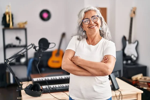 Middle age woman musician standing with arms crossed gesture at music studio
