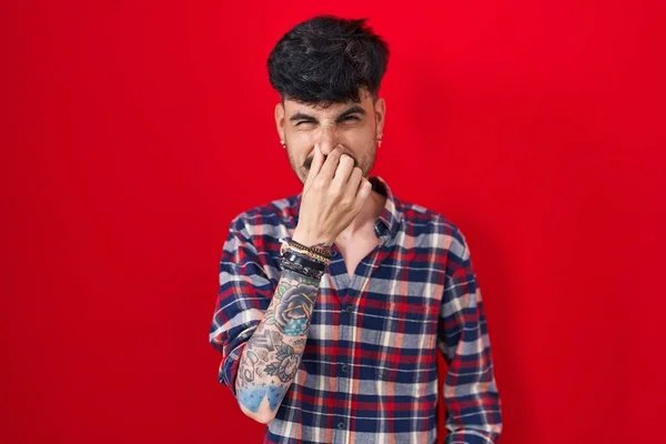 Young Hispanic Man Beard Standing Red Background Smelling Something Stinky — 스톡 사진