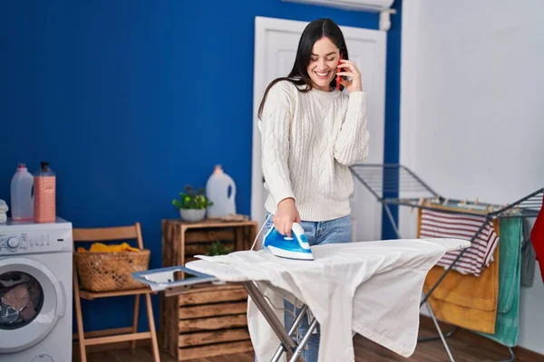 Mujer Joven Hablando Teléfono Inteligente Planchado Ropa Sala Lavandería — Foto de Stock