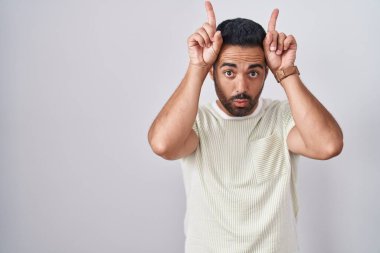 Sakallı İspanyol bir adam izole edilmiş arka planda duruyor ve parmağıyla boynuz gibi hareket ediyor. 