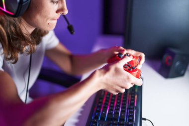 Young beautiful hispanic woman streamer playing video game using joystick at gaming room