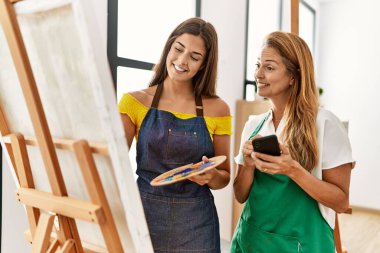 Anne ve kızı resim stüdyosunda akıllı telefon ve çizim kullanıyor.