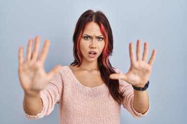 Young caucasian woman wearing pink sweater over isolated background doing stop gesture with hands palms, angry and frustration expression 