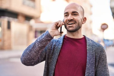 Genç adam gülümsüyor. Kendine güveniyor. Sokakta akıllı telefondan konuşuyor.