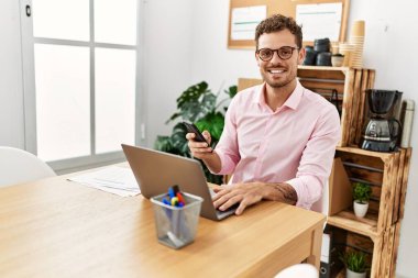 Ofiste akıllı telefon kullanan, kendine güvenen genç bir İspanyol.