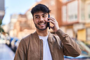Genç İspanyol adam gülümsüyor. Kendine güveniyor. Sokakta akıllı telefondan konuşuyor.