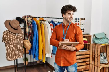 Genç İspanyol esnaf gülümsüyor. Giyim mağazasında çalışan panoya mutlu yazılar yazıyor..