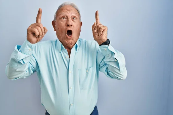 Senior Man Grey Hair Standing Blue Background Amazed Surprised Looking — Stockfoto