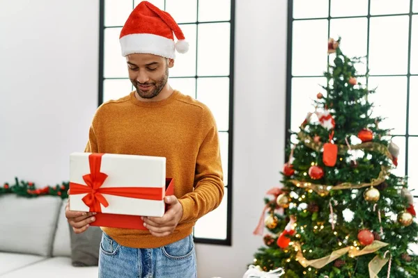 Young Arab Man Smiling Happy Unboxing Gift Standing Christmas Tree — Stock Photo, Image