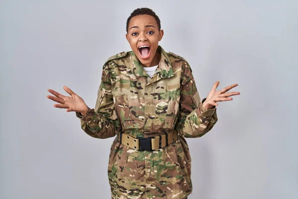 stock image Beautiful african american woman wearing camouflage army uniform celebrating crazy and amazed for success with arms raised and open eyes screaming excited. winner concept 