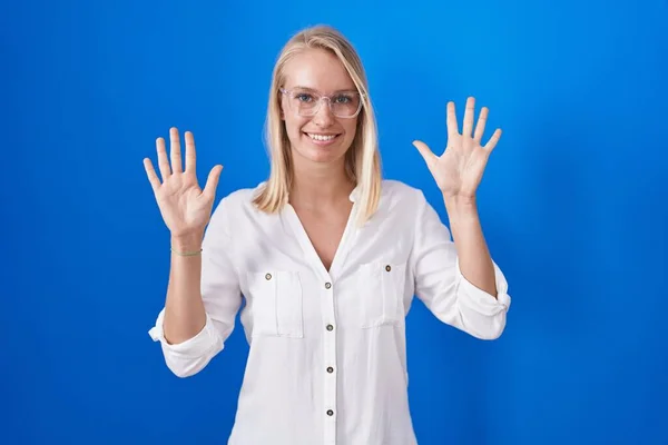 Mladá Kavkazská Žena Stojící Nad Modrým Pozadím Ukazující Ukazující Prsty — Stock fotografie
