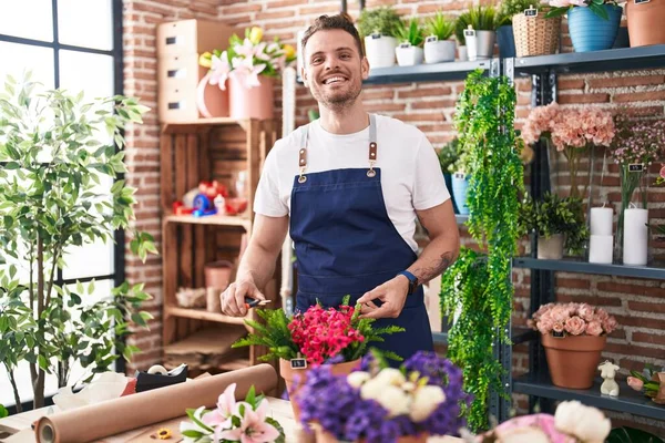 Young hispanic man florist cutting plants at florist