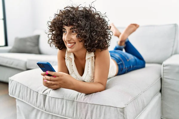 年轻的中东女人在家里用智能手机充满自信地微笑 — 图库照片