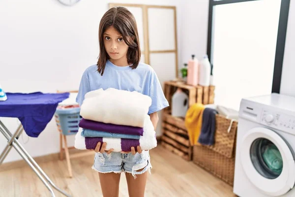 Young hispanic girl holding folded laundry skeptic and nervous, frowning upset because of problem. negative person.