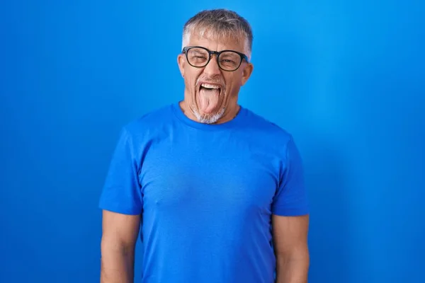 Mavi Arka Planda Dikilen Gri Saçlı Komik Bir Ifadeyle Dilini — Stok fotoğraf