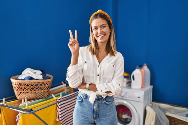 Young Blonde Woman Laundry Room Smiling Happy Face Winking Camera — Stockfoto
